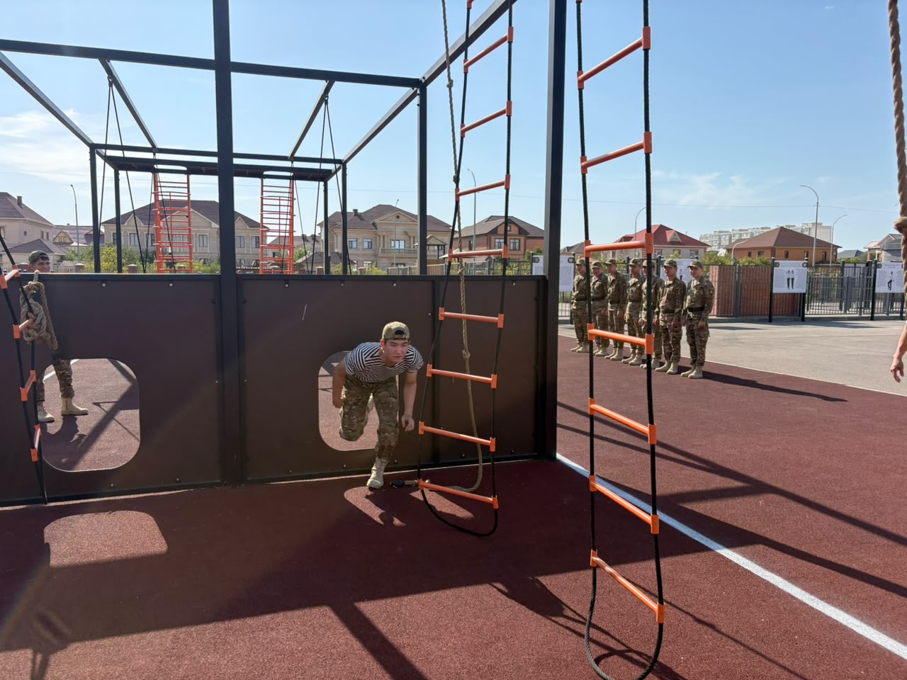 Cadet climbing through an obstacle wall window